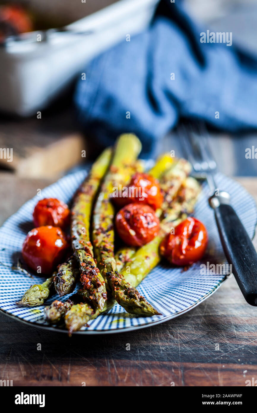 Asperges vertes grillées avec des tomates cerises sur une plaque Banque D'Images