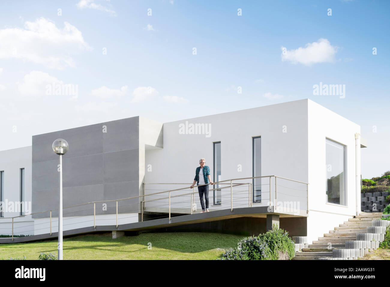 Homme debout devant sa maison moderne Banque D'Images Homme debout devant sa maison moderne Banque D'Images