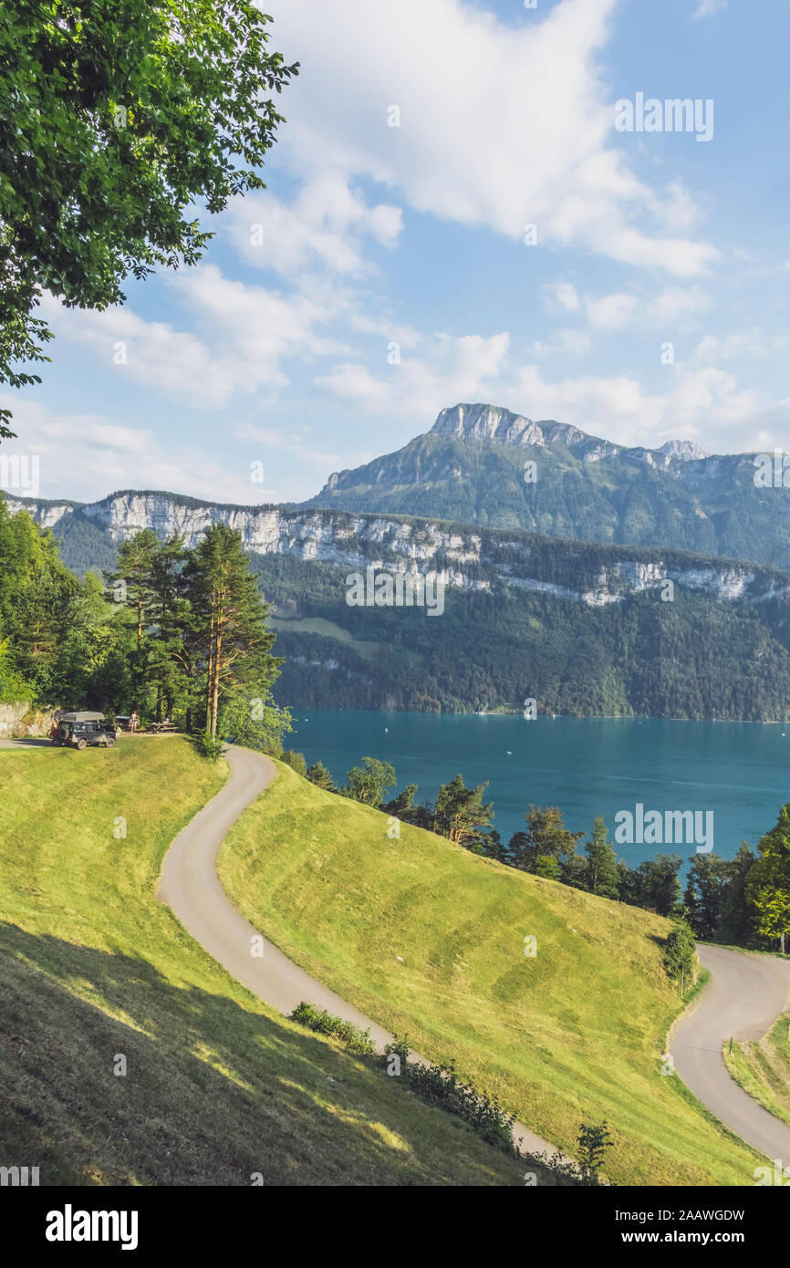 La Suisse, Lucerne, Schwyz, route sinueuse avec une haute falaise boisée et le lac de Lucerne en arrière-plan Banque D'Images