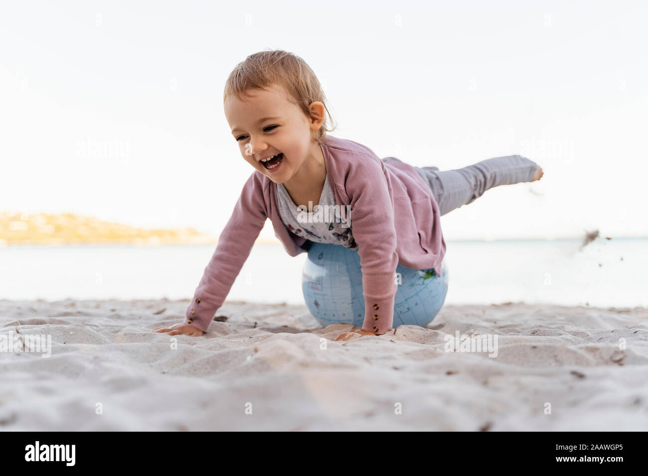 Portrait of laughing petite fille en équilibre sur terre ballon de plage Banque D'Images