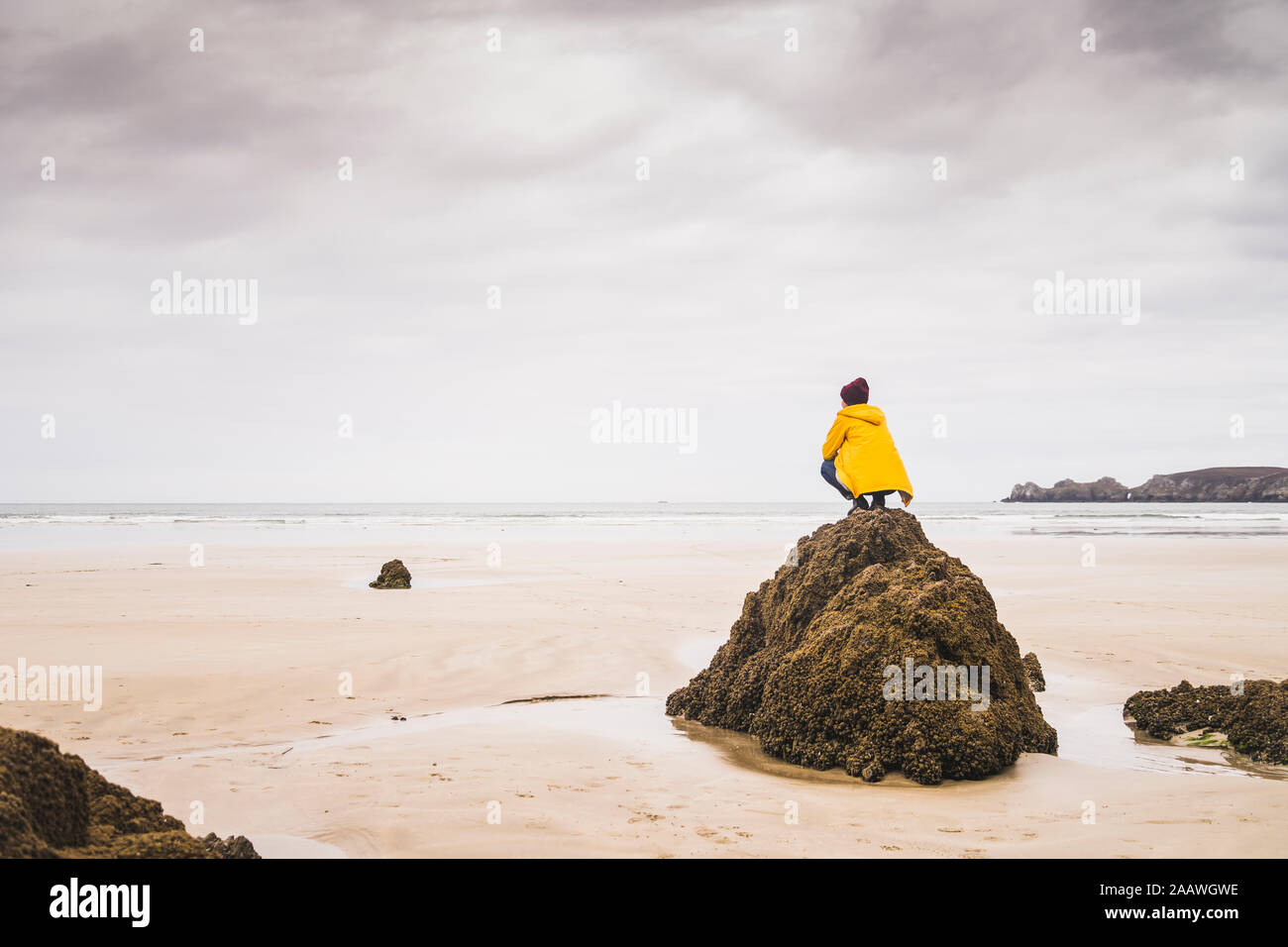 Jeune femme portant Veste pluie jaune sur la plage, Bretagne, France Banque D'Images