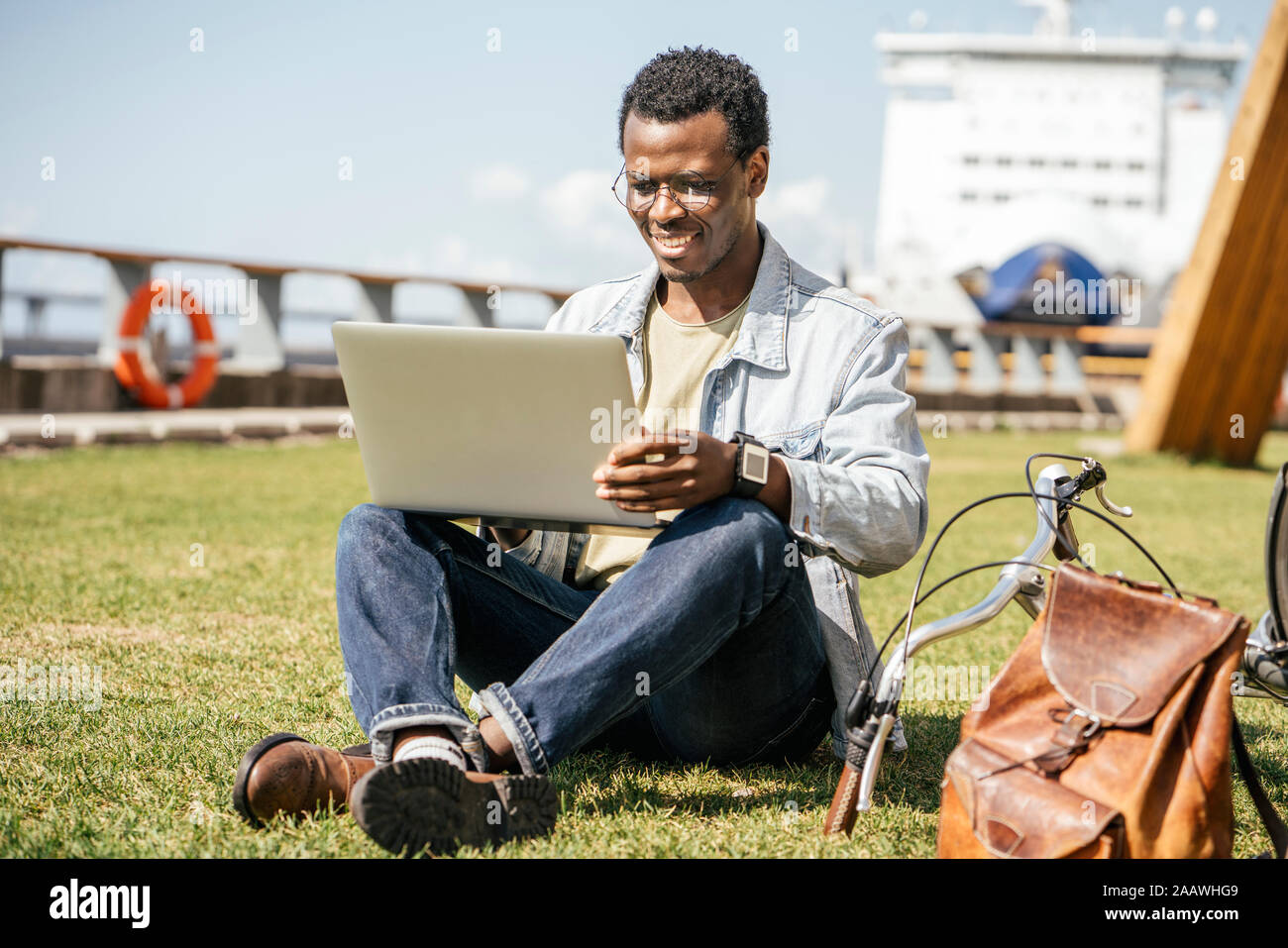 Young man sitting on grass, using laptop Banque D'Images