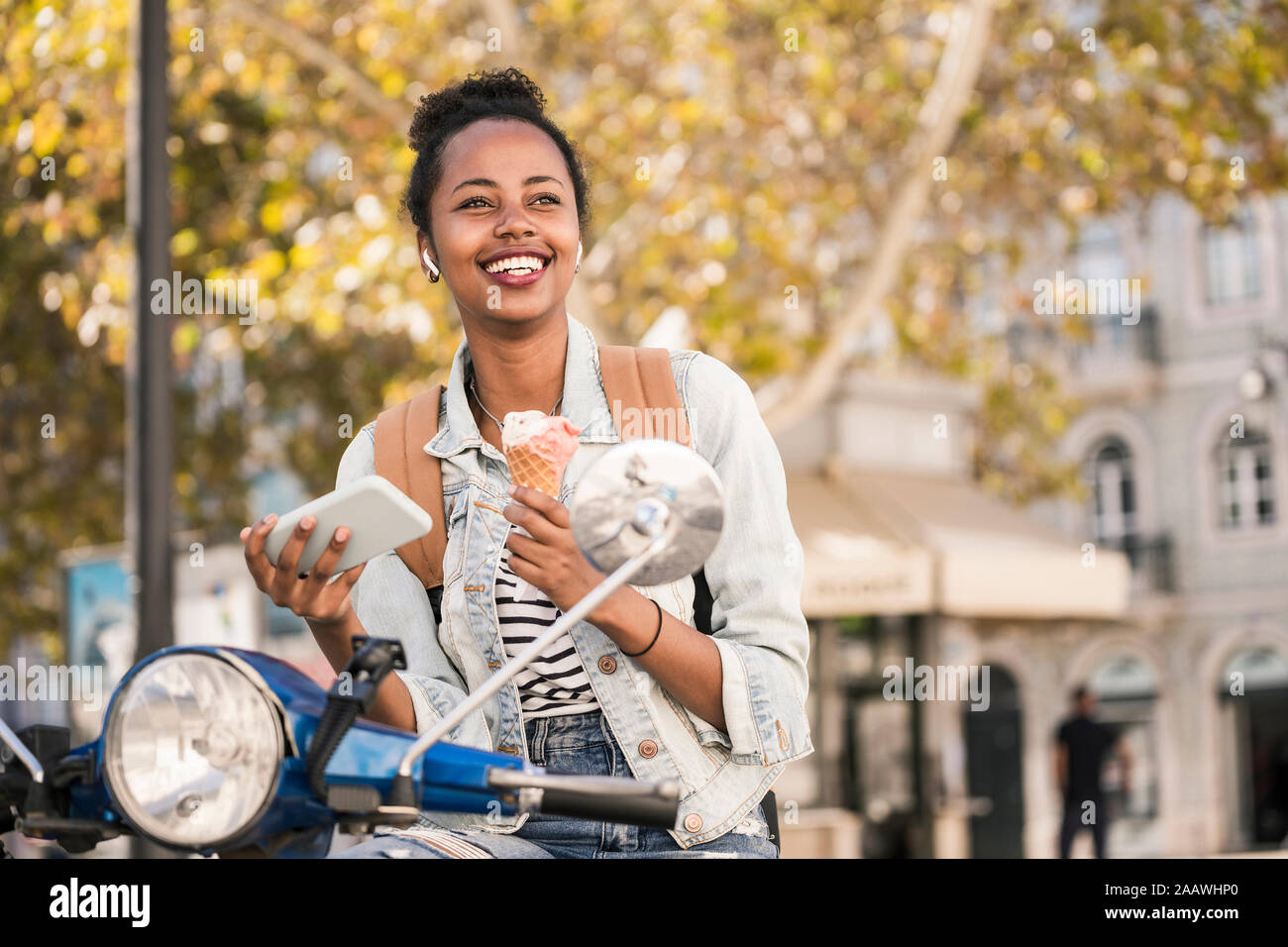 Happy young woman with scooter tout en étant dans la ville, Lisbonne, Portugal Banque D'Images