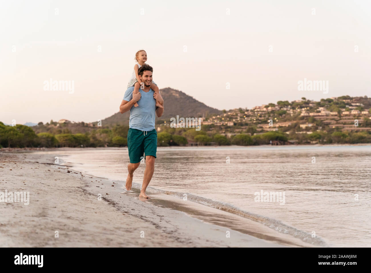 Heureux père fille portant sur les épaules sur la plage au coucher du soleil Banque D'Images