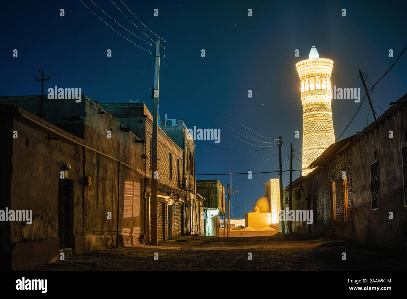 Rue avec des bâtiments d'habitation contre Grand Minaret Kalon de Boukhara, en Ouzbékistan. C'est un minaret de la Po-i-mosquée Kalyan dans Buxo complexes Banque D'Images