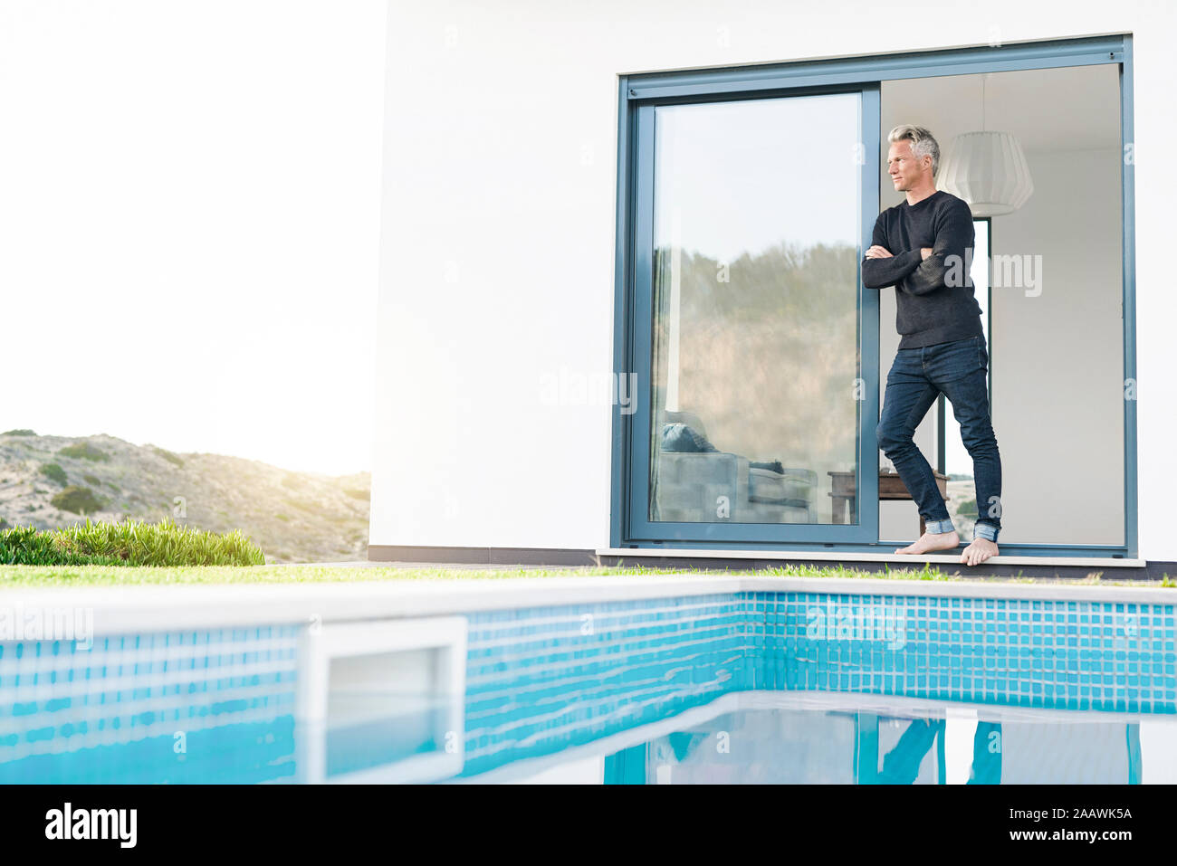 L'homme intelligent se tenait devant sa maison moderne avec piscine à la recherche sur les paysages Banque D'Images L'homme intelligent se tenait devant sa maison moderne avec piscine à la recherche sur les paysages Banque D'Images
