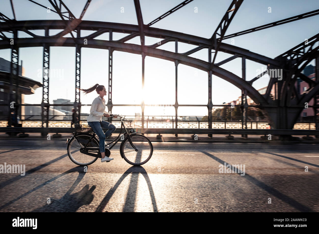 Les jeunes cyclistes sur un pont au coucher du soleil Banque D'Images