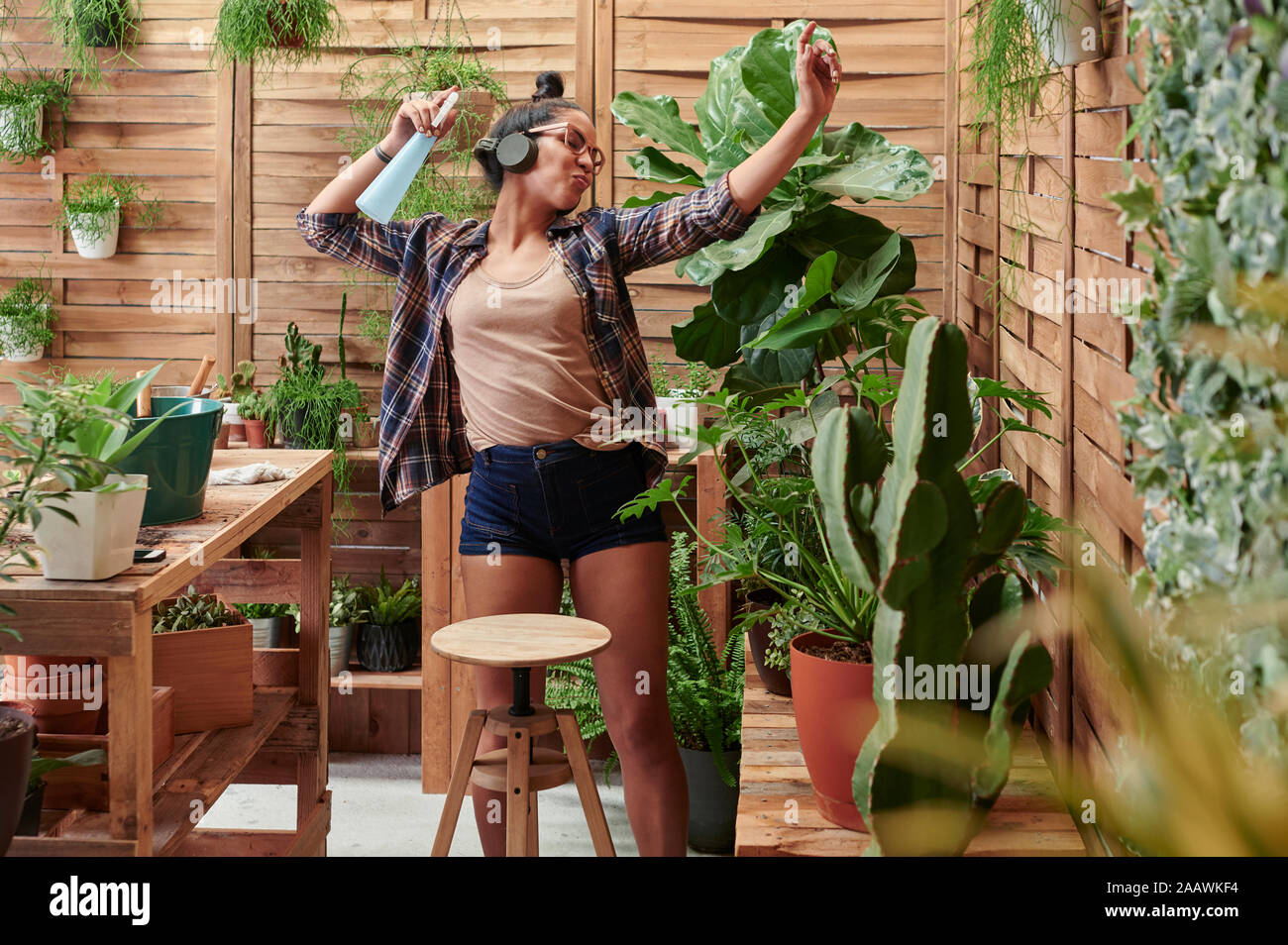 Happy young woman dancing sur sa terrasse tout en faisant du jardinage Banque D'Images