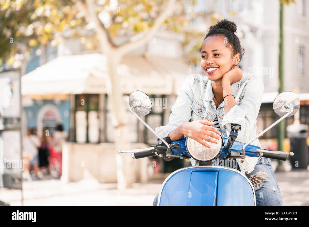 Happy young woman with motor scooter dans la ville, Lisbonne, Portugal Banque D'Images