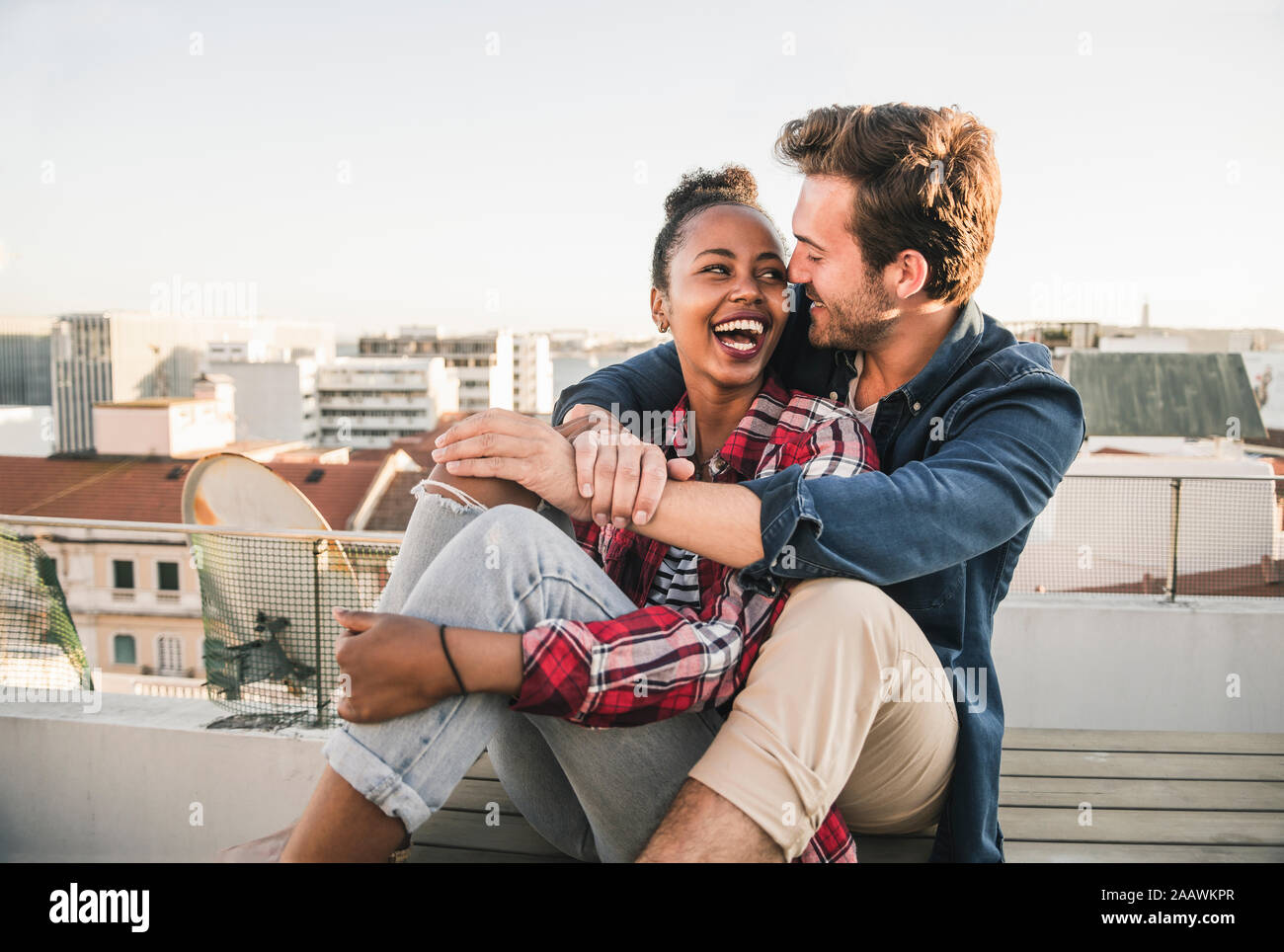 Happy young couple sitting on toit dans la soirée Banque D'Images