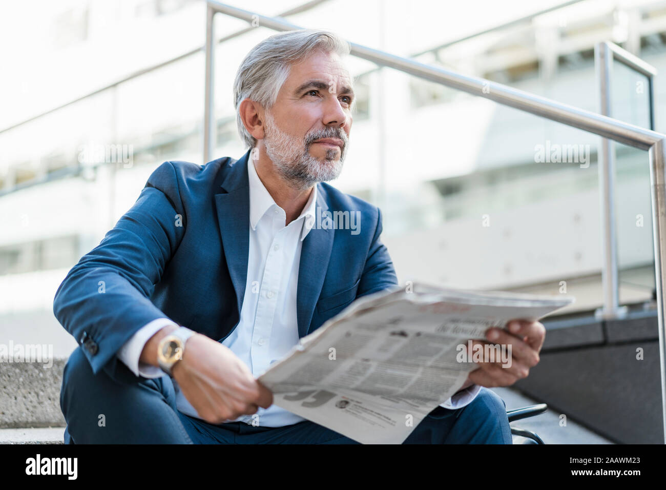 Mature businessman sitting on stairs dans la ville avec du papier journal Banque D'Images