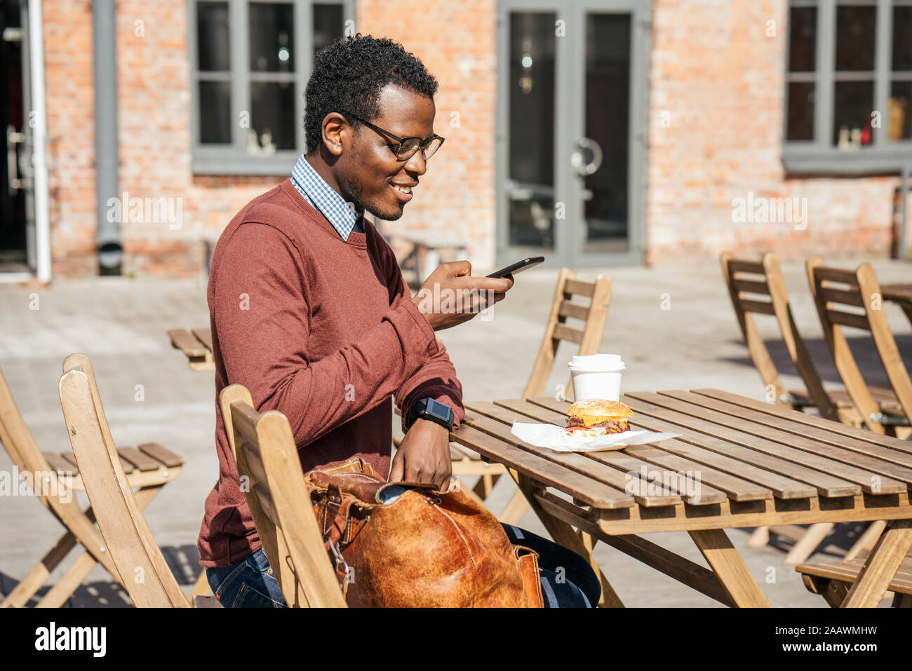 Jeune homme à prendre des photos de son cheeseburger avec son smartphone Banque D'Images