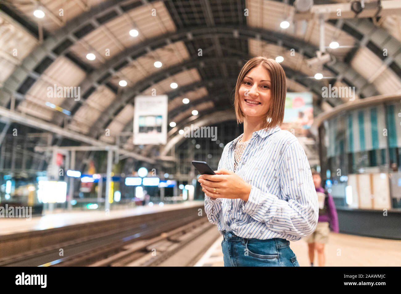 Young smiling woman using smartphone sur gare Banque D'Images