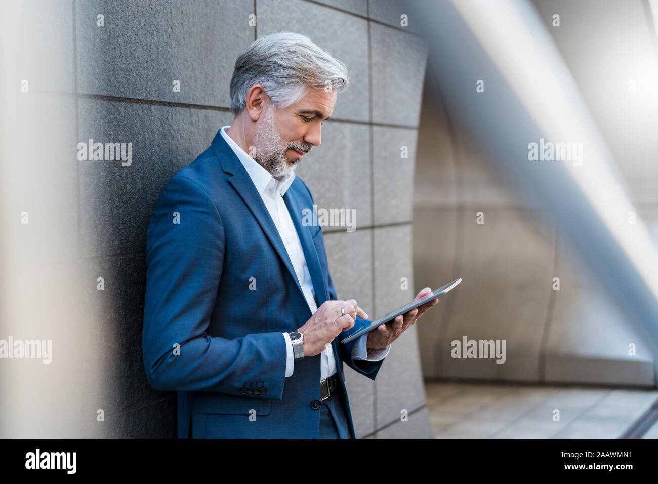 Businessman standing à un mur à l'aide de tablet Banque D'Images