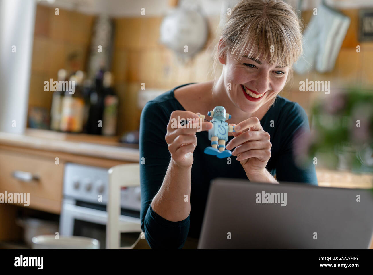 Portrait of laughing woman avec petit robot et l'ordinateur portable dans la cuisine Banque D'Images