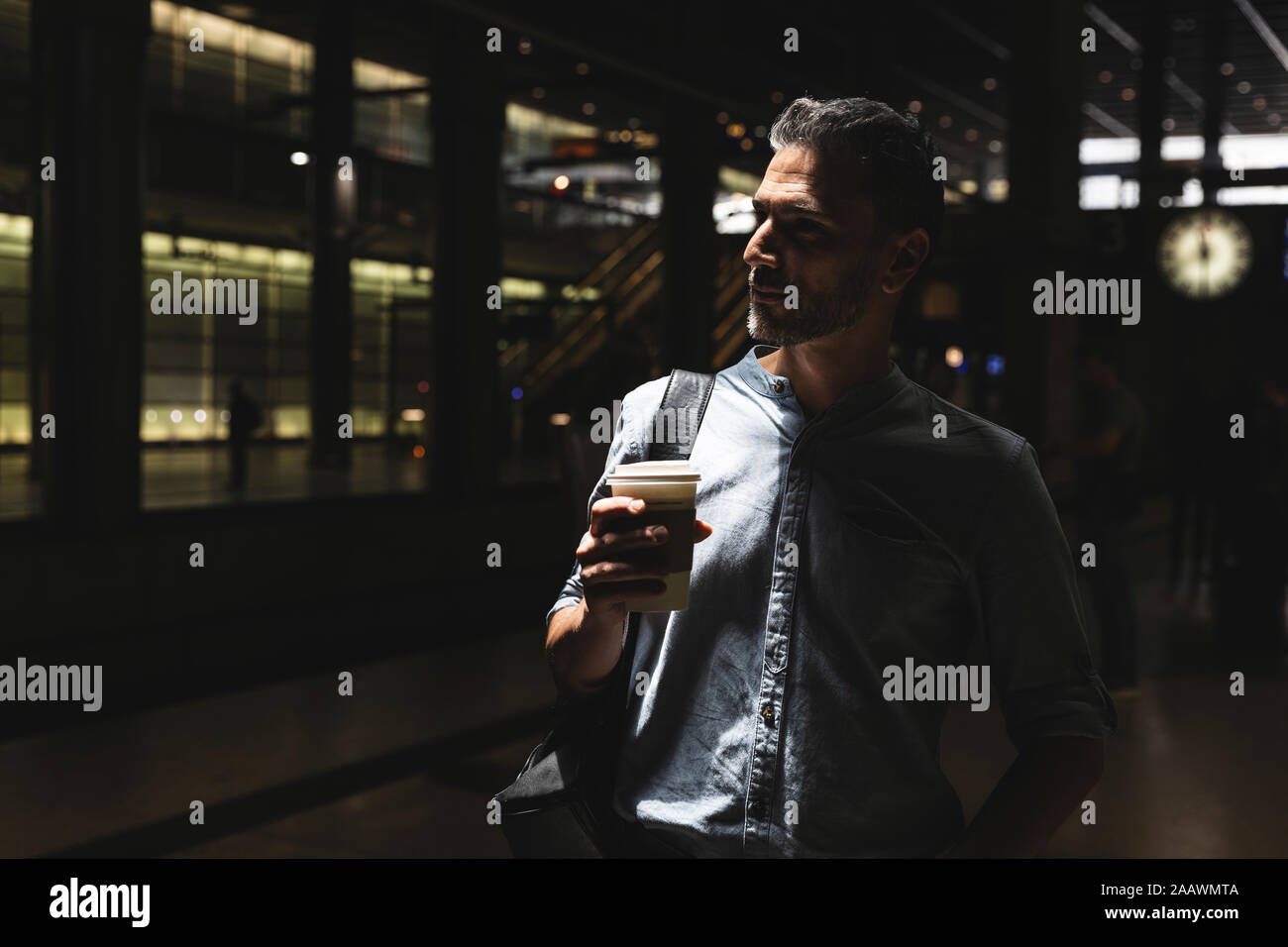 Homme avec un café à emporter à la station de Shadow, Berlin, Allemagne Banque D'Images
