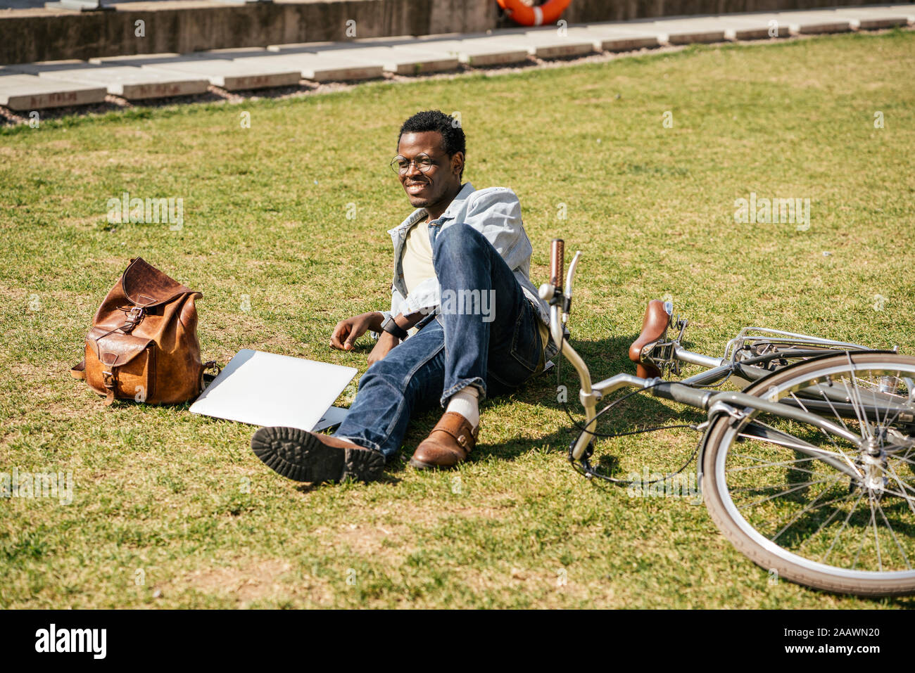 Jeune homme avec alptop et location, lying on grass Banque D'Images