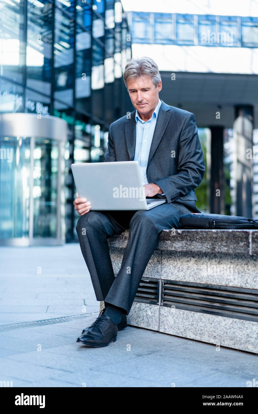 Mature businessman using laptop in the city Banque D'Images