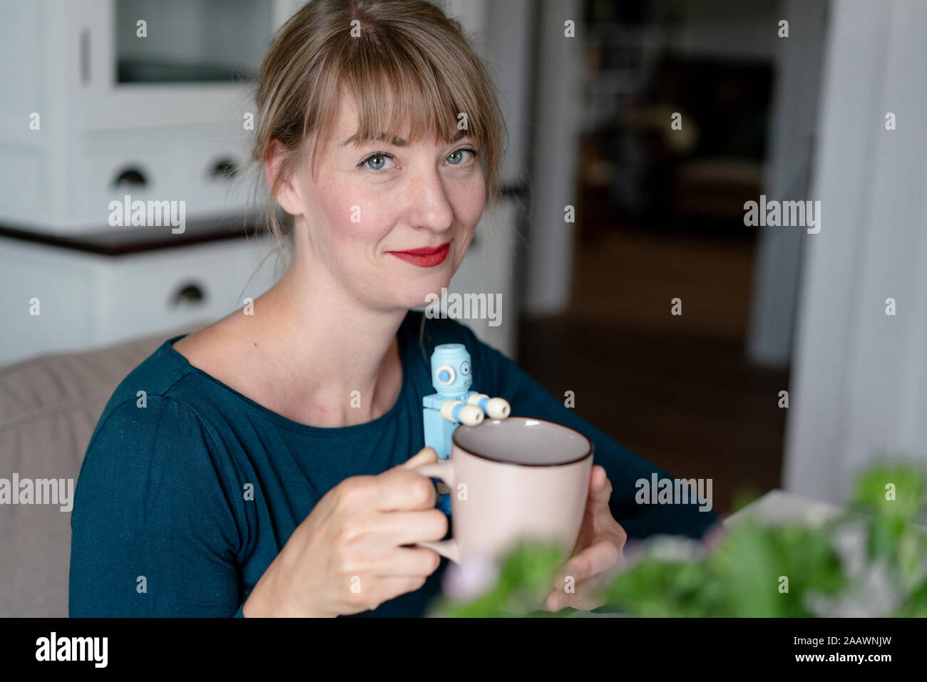 Portrait of smiling woman holding mug avec petit robot Banque D'Images