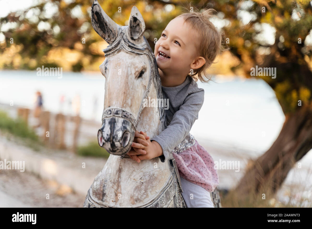 Happy cute girl sitting on cheval de bois Banque D'Images Happy cute girl sitting on cheval de bois Banque D'Images