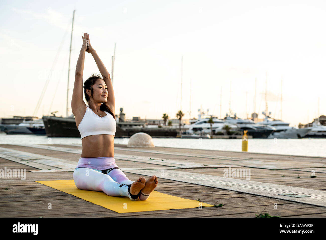 Asian woman practicing yoga on a pier à l'Harbour Banque D'Images