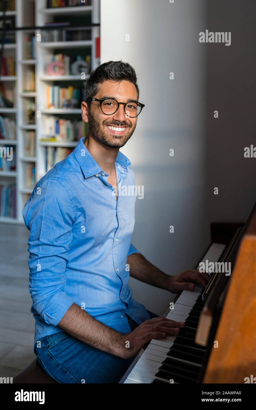 Portrait of happy young man playing piano à la maison Banque D'Images