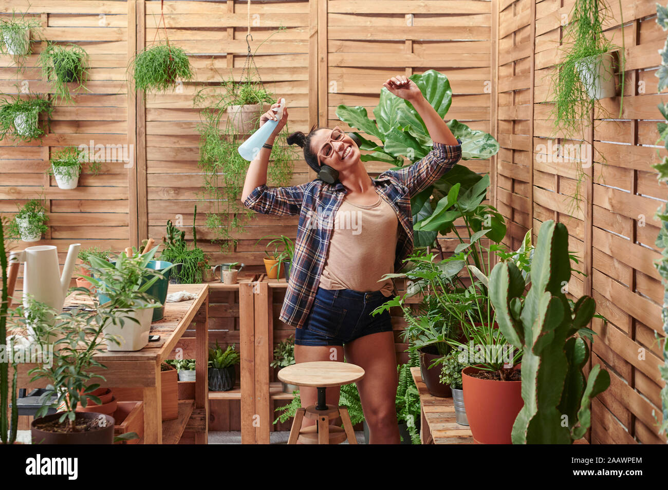 Happy young woman dancing sur sa terrasse tout en faisant du jardinage Banque D'Images