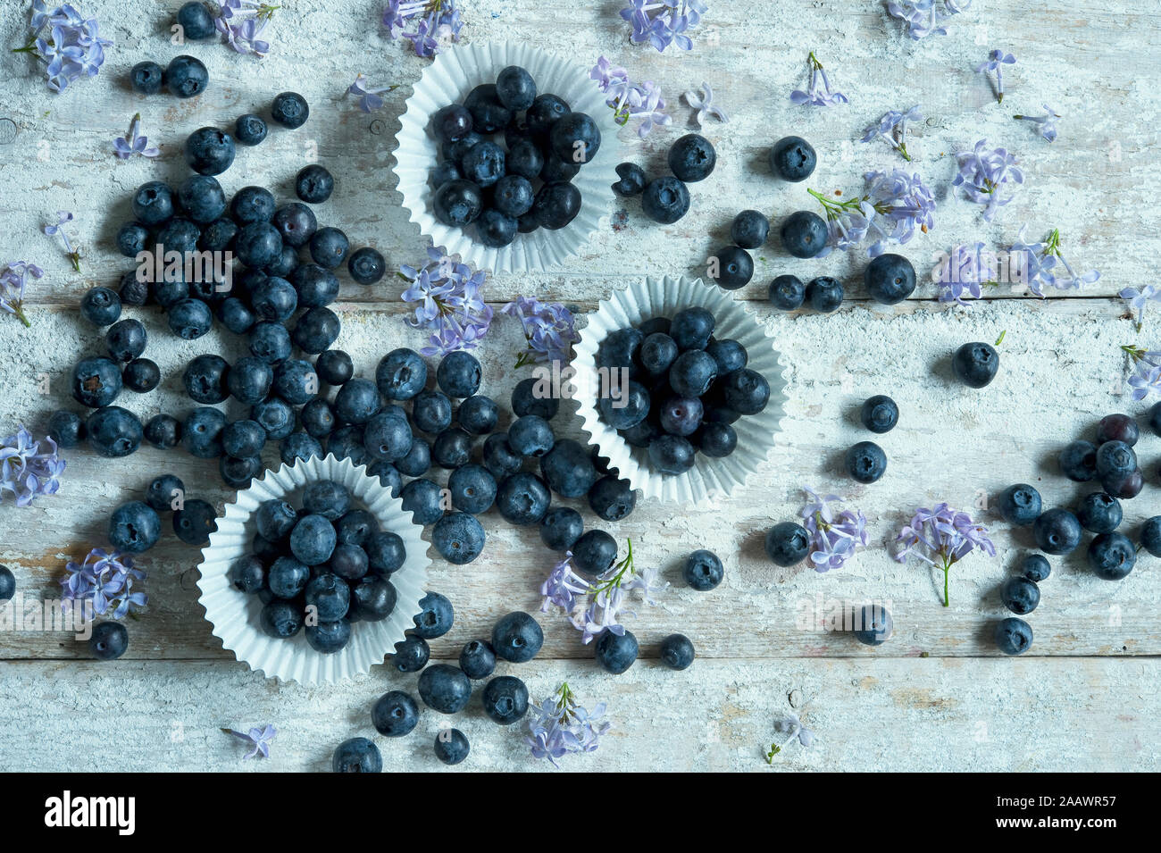 Tourné directement au-dessus de bleuets en fleurs avec les détenteurs de cupcake sur table en bois Banque D'Images