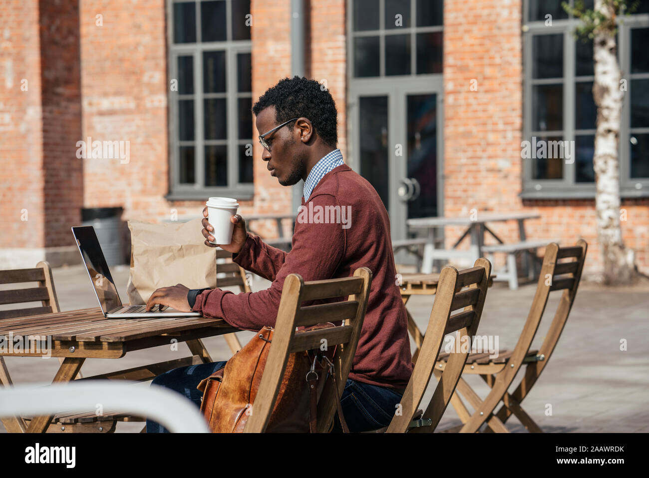 Jeune homme à l'aide d'ordinateur portable dans un café, boire du café Banque D'Images