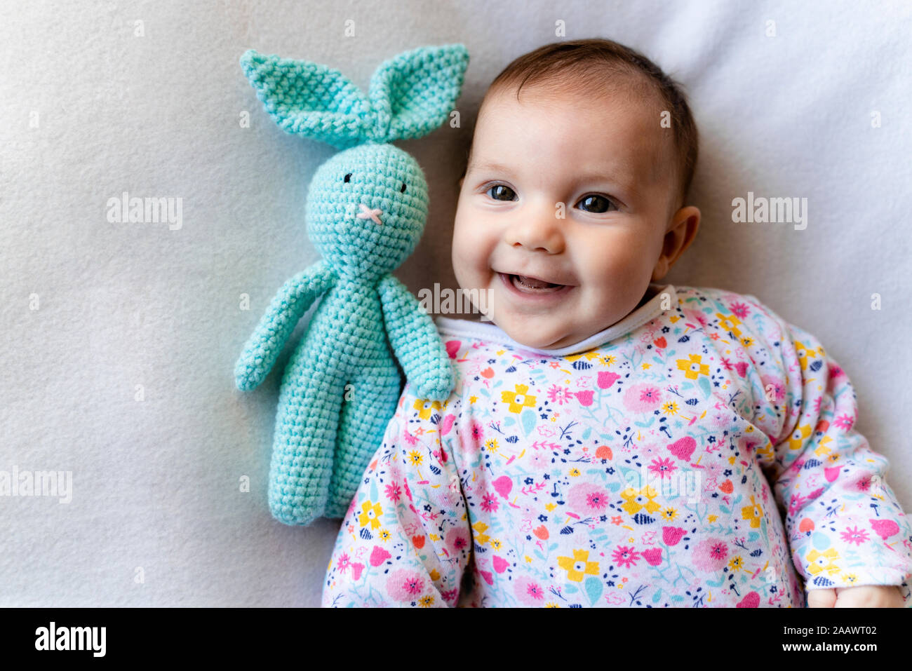 Baby Girl avec un lapin toy lying on bed Banque D'Images