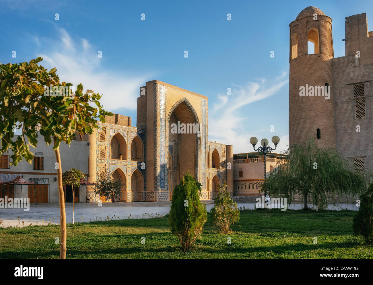 Parc avec arbres et herbe verte contre Ulugh Beg Madrasa de Boukhara, Ouzbékistan Banque D'Images