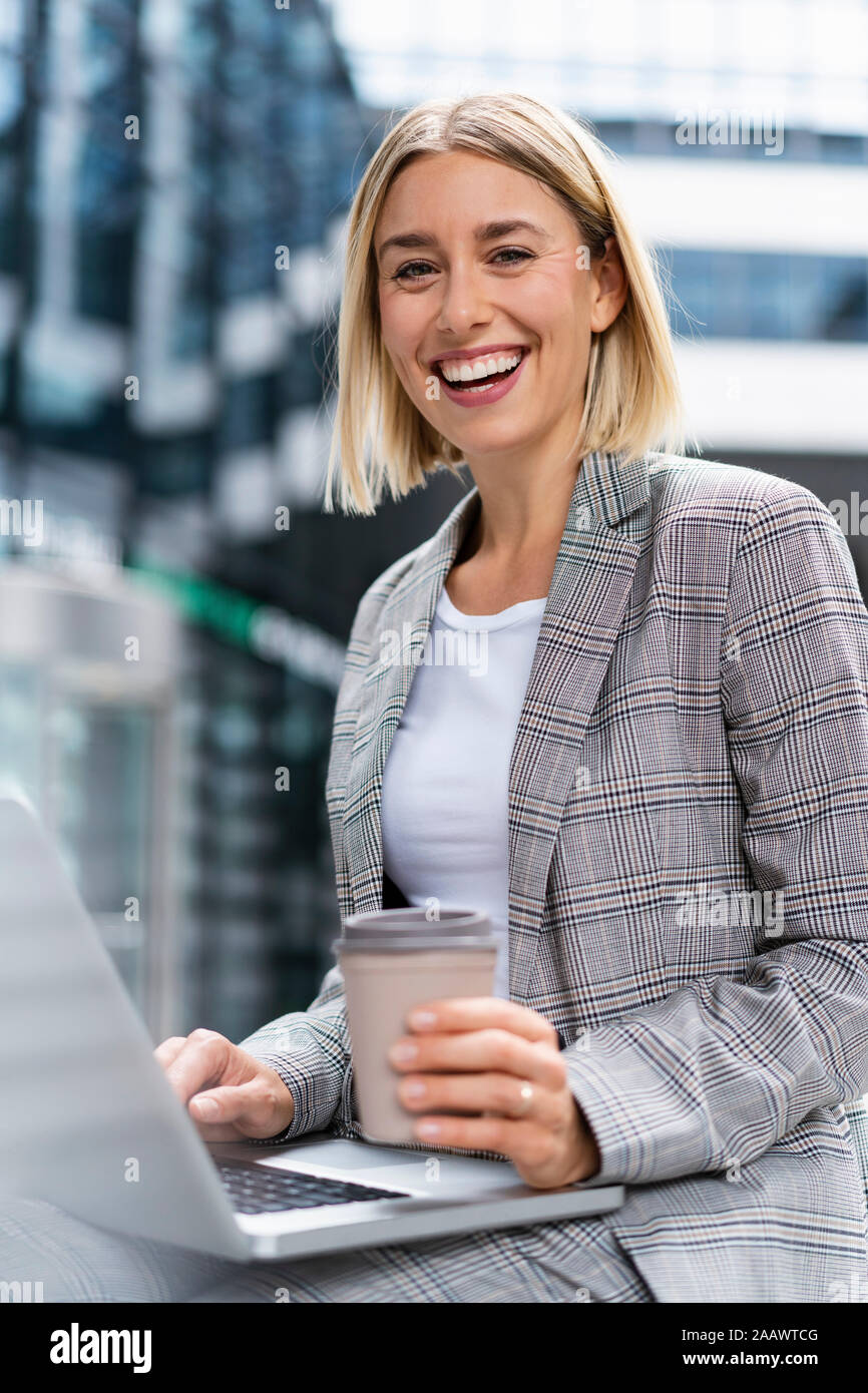 Portrait of happy young businesswoman with laptop dans la ville Banque D'Images