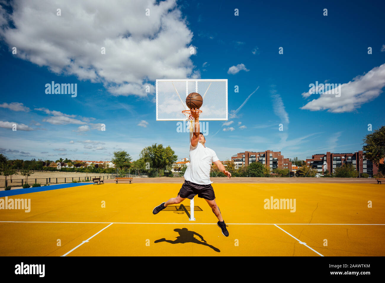 L'homme jouant au basket-ball sur cour jaune, tremper Banque D'Images