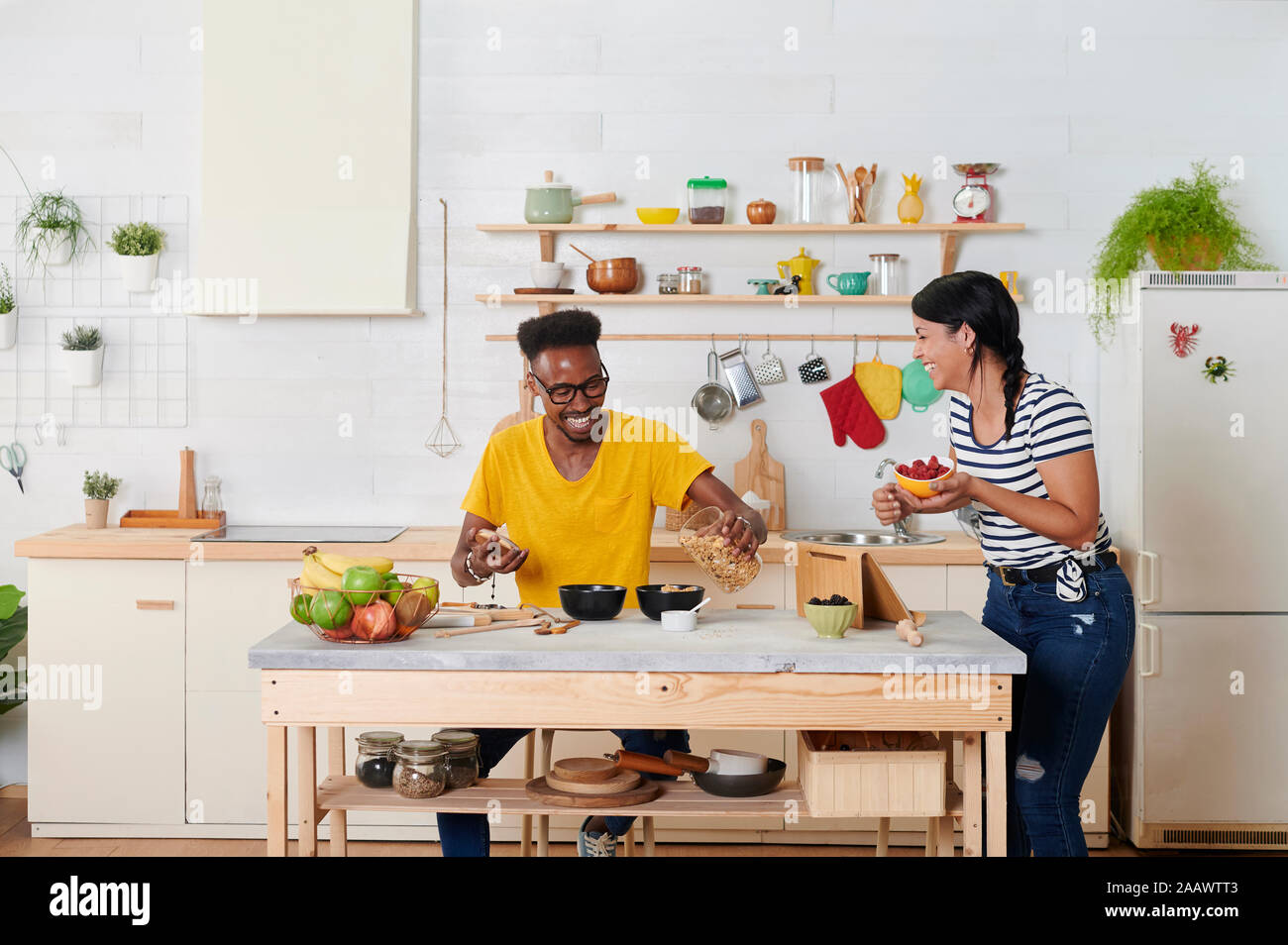 Couple laughing multiethnique, déjeunant ensemble dans la cuisine Banque D'Images