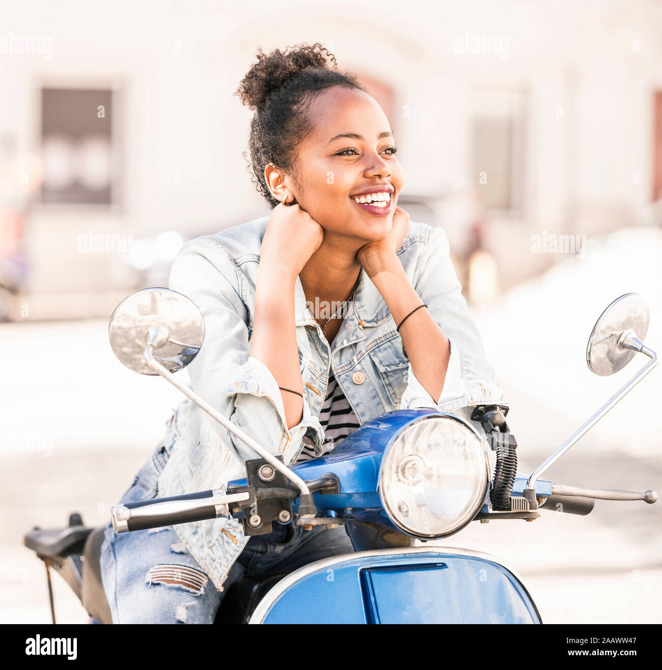 Happy young woman with motor scooter dans la ville, Lisbonne, Portugal Banque D'Images