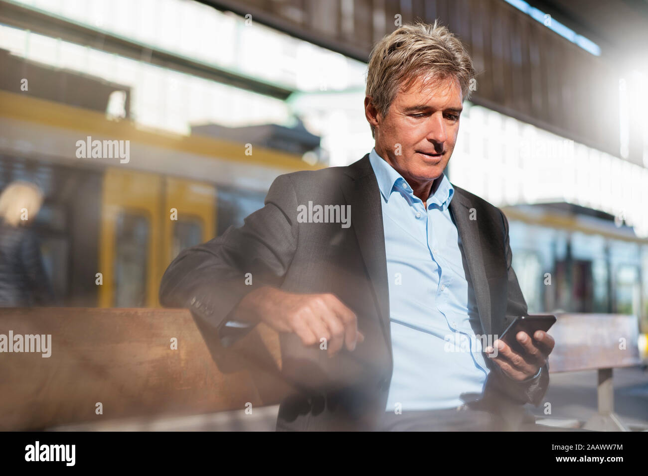 Mature businessman en attente à la plate-forme using cell phone Banque D'Images