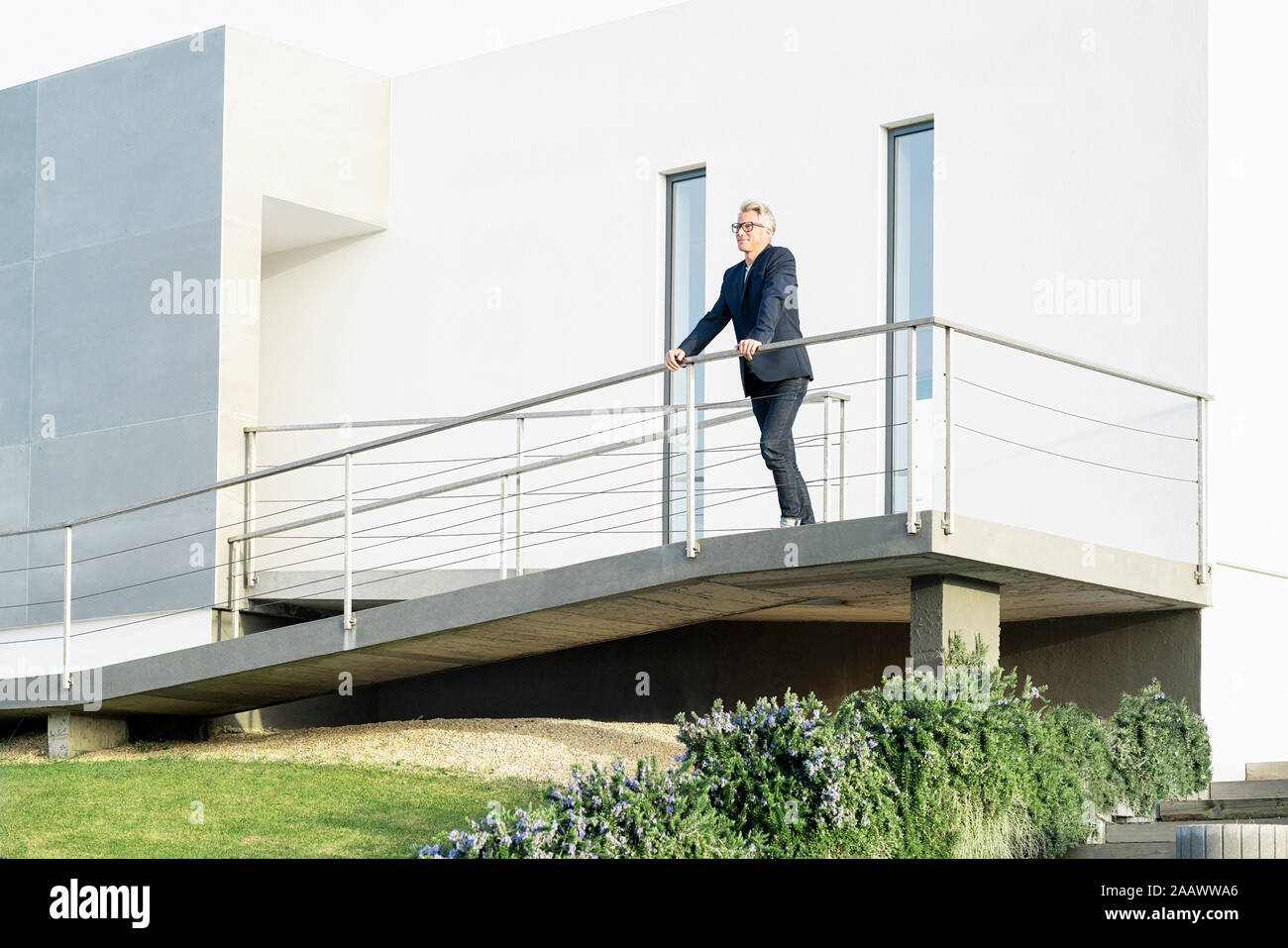 Businessman debout devant sa maison moderne à la recherche autour de Banque D'Images Businessman debout devant sa maison moderne à la recherche autour de Banque D'Images