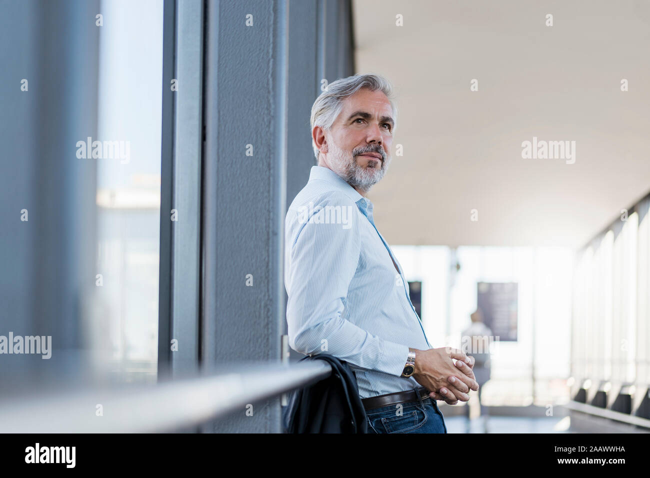 Mature businessman leaning on railing dans une zone de passage Banque D'Images