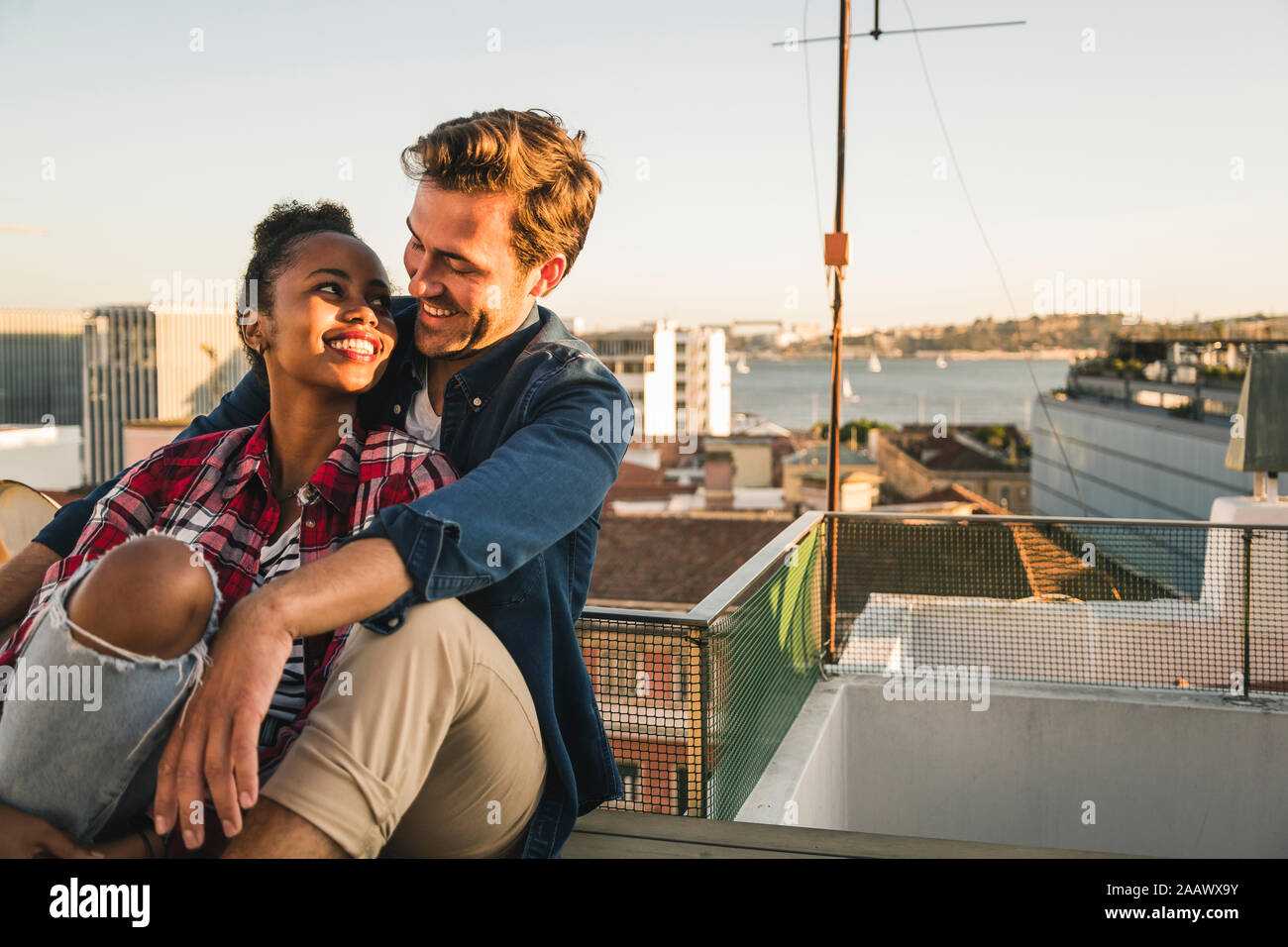 Happy young couple sitting on toit dans la soirée Banque D'Images