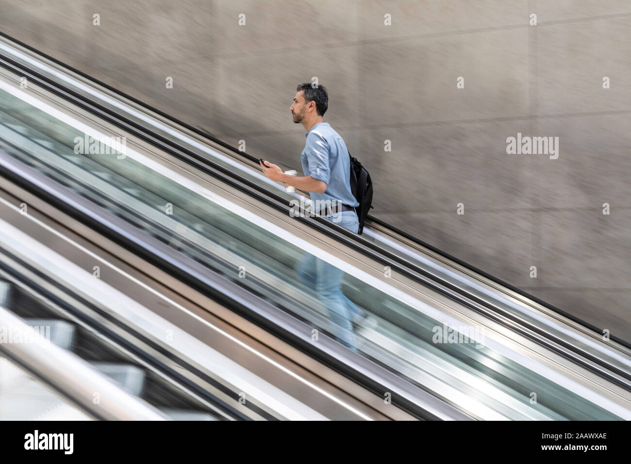 Homme d'affaires marchant vers l'escalier mécanique dans la ville, Berlin, Allemagne Banque D'Images