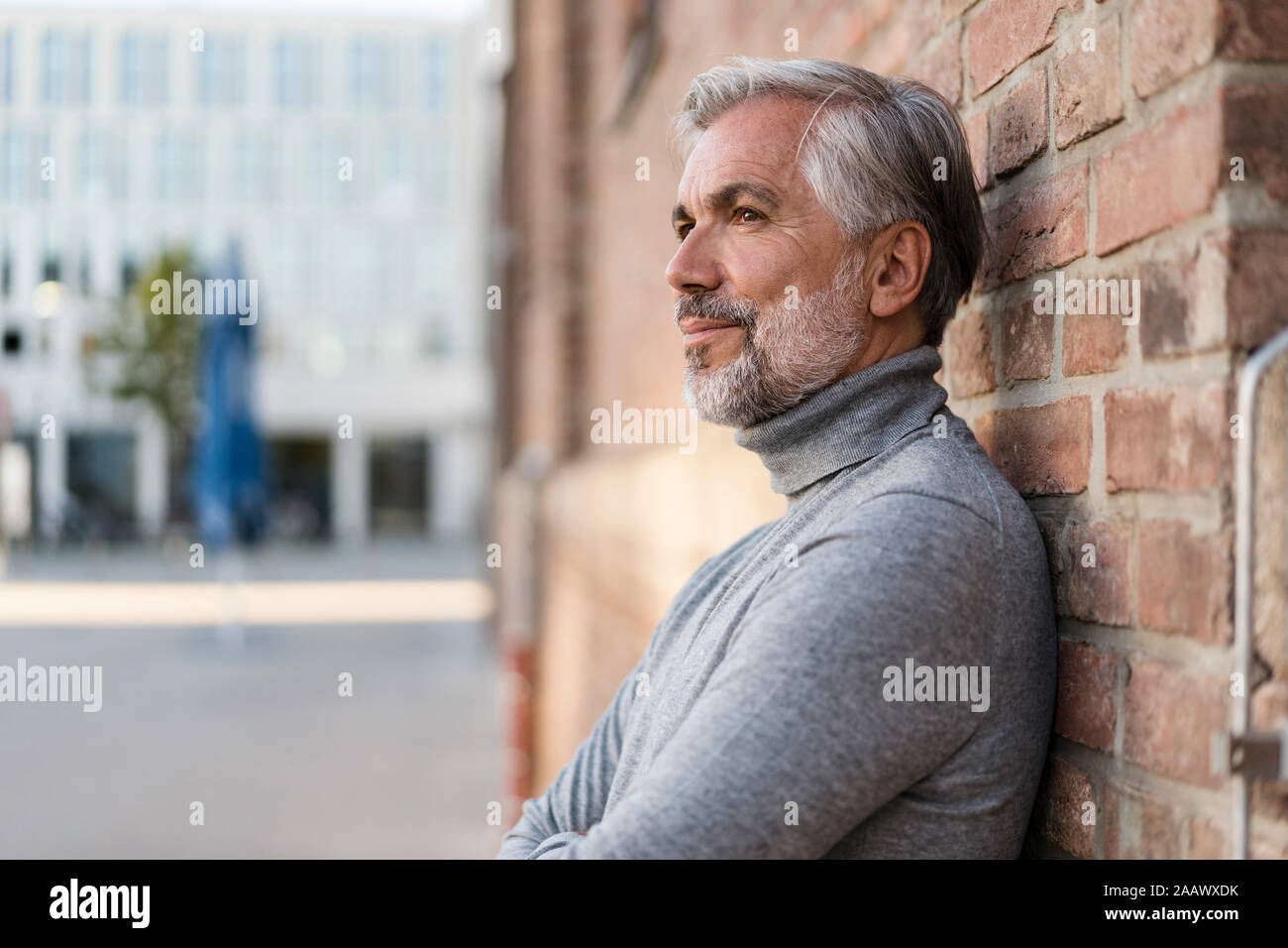 Portrait of mature businessman leaning à un mur de briques Banque D'Images