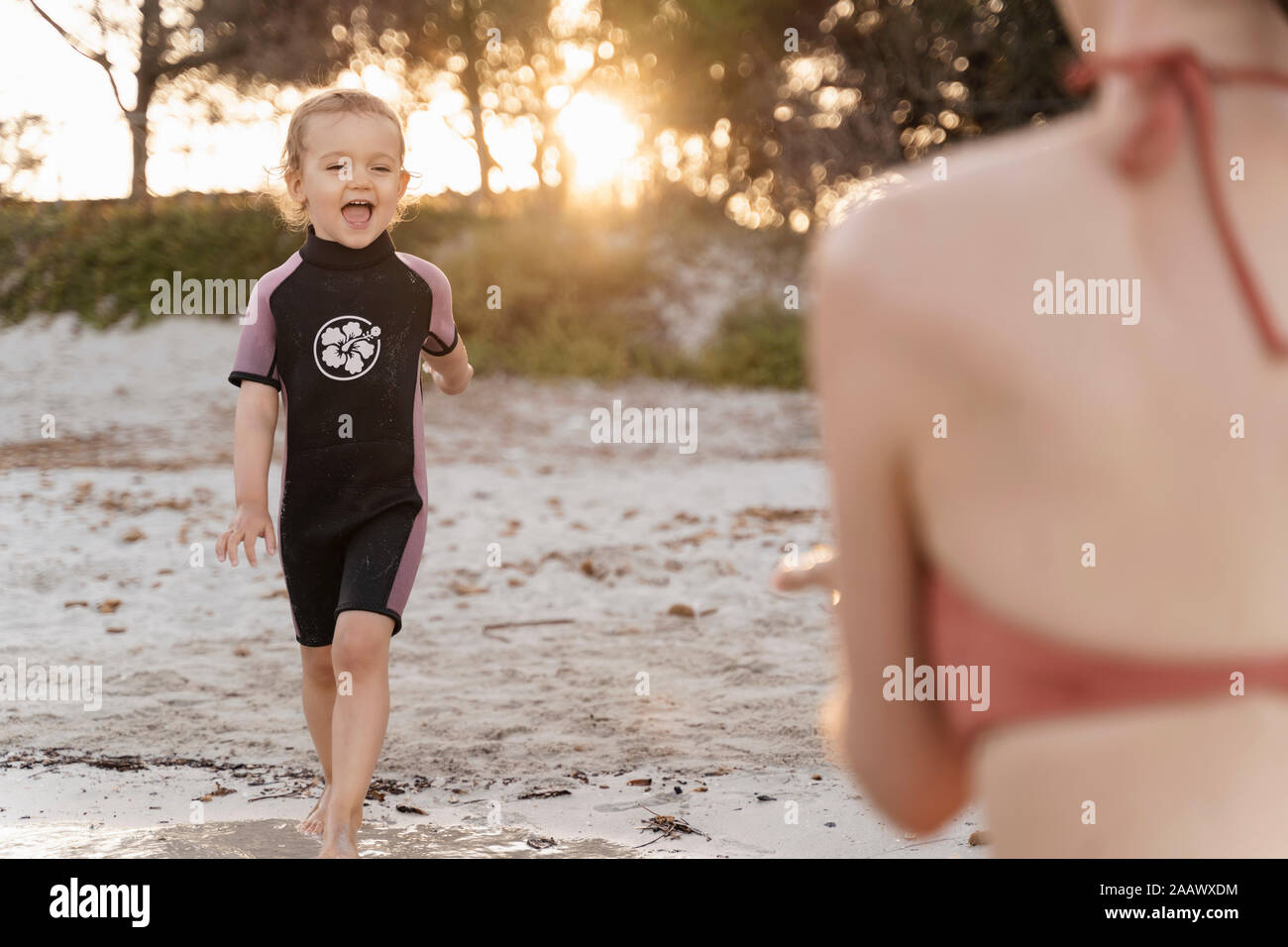 Happy girl avec sa mère sur la plage au coucher du soleil Banque D'Images