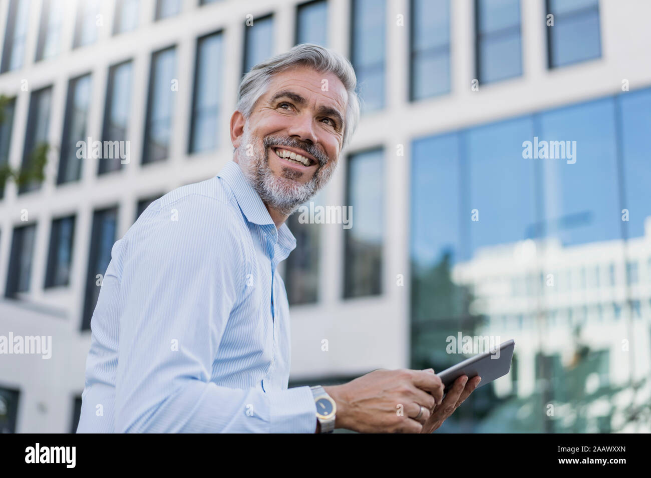 Smiling mature businessman using tablet dans la ville Banque D'Images