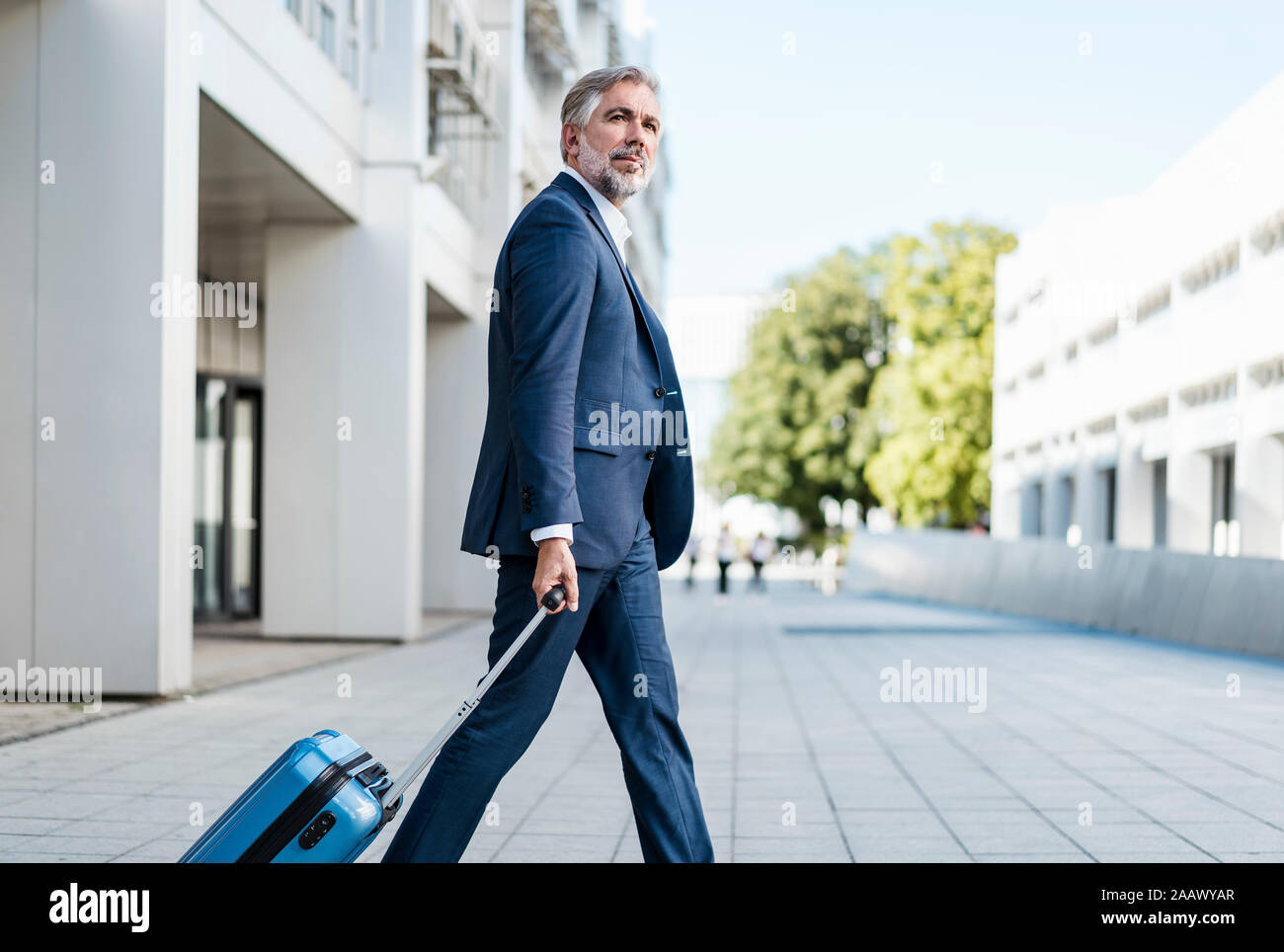 Mature businessman avec valise roulant sur le rendez-vous dans la ville Banque D'Images