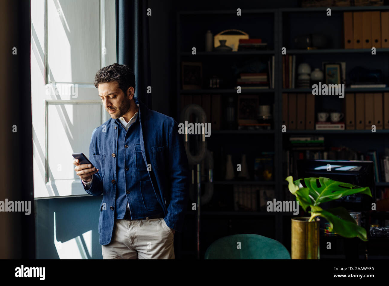 Homme debout dans son bureau, using smartphone Banque D'Images