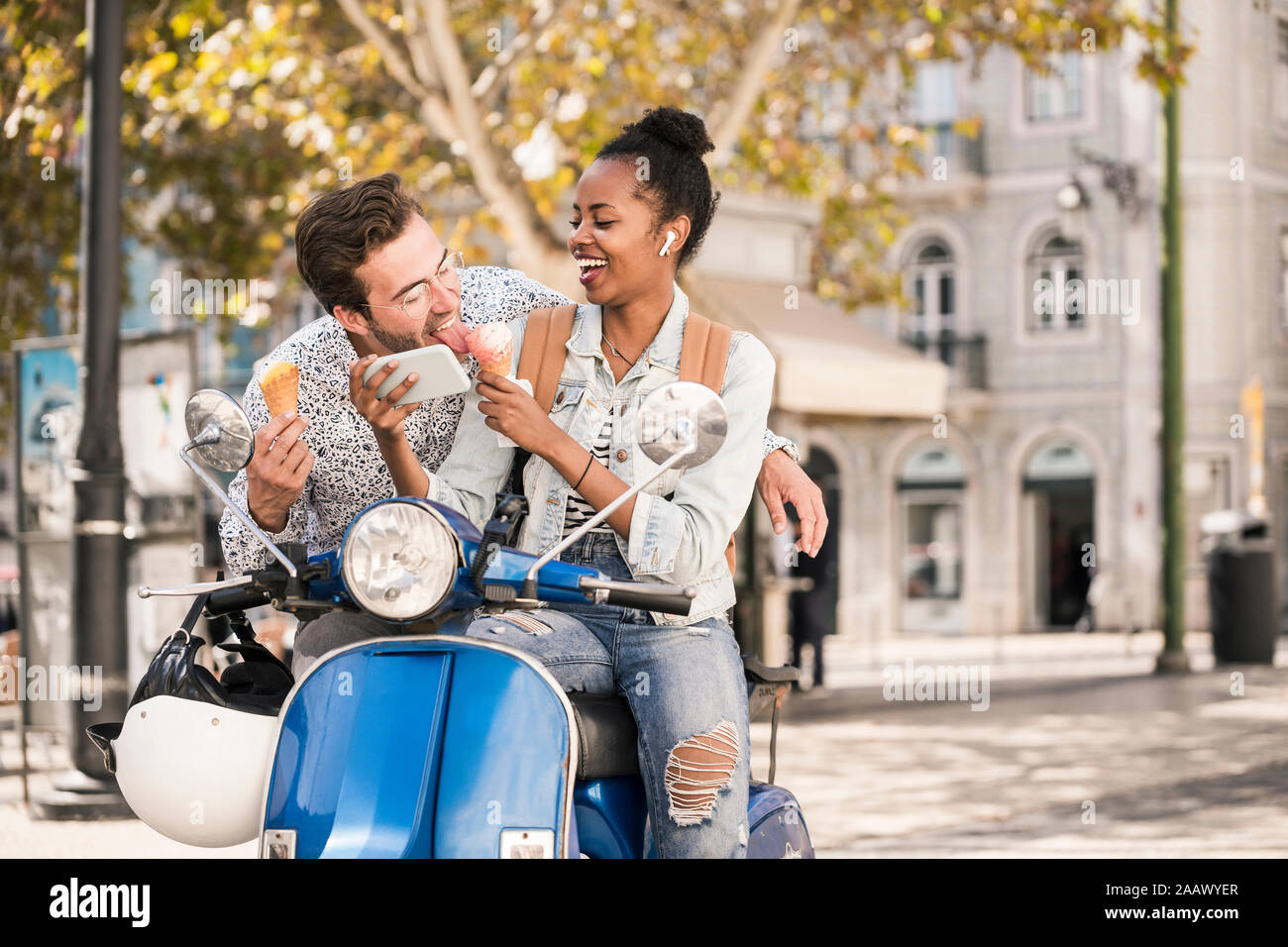 Happy young couple with motor scooter, la crème glacée et du téléphone mobile dans la ville, Lisbonne, Portugal Banque D'Images