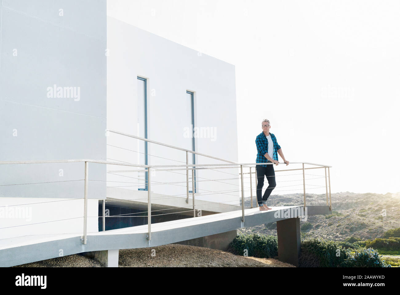 Homme debout devant sa maison moderne à la recherche sur les paysages Banque D'Images Homme debout devant sa maison moderne à la recherche sur les paysages Banque D'Images