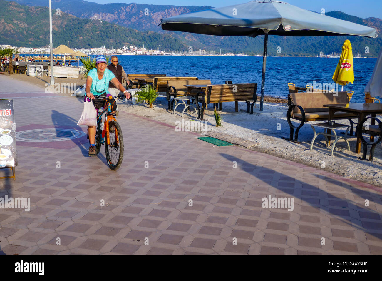 Femme à vélo sur front de mer, Mamaris, une ville balnéaire populaire dans le sud de la Turquie, le temps d'automne. Banque D'Images