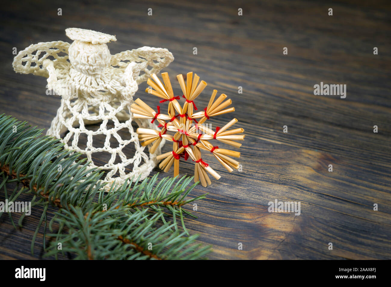 Fond de Noël avec des ornements faits à la main, y compris un ange de bonneterie thread et une paille star attaché avec de la ficelle rouge sur un bois rustique background Banque D'Images