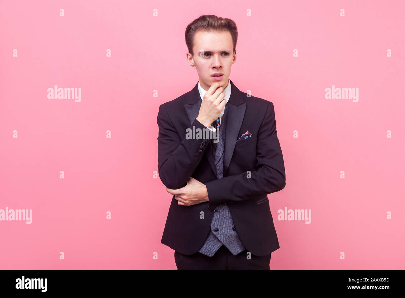 Permettez-moi de penser. Portrait d'homme intelligent dans cher costume et avec décote élégant toucher son menton et à côté avec perplexe face, ponde Banque D'Images
